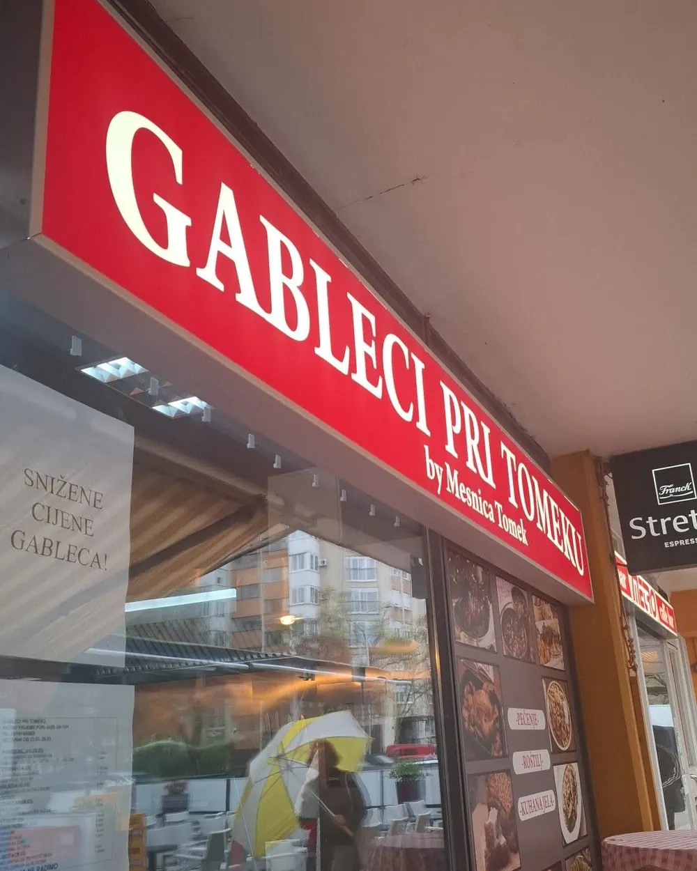 Ulaz u Gablece Pri Tomeku s crvenim natpisom i stolovima